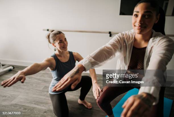 female personal trainer coaches her female student how to squat - dancers exercising teacher stockfoto's en -beelden