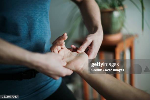 close up of massage therapist massaging the hand of a patient. - black massage therapist fotografías e imágenes de stock