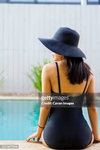young woman wearing a black hat while is sitting near by pool - beautiful black women in bathing suits stock pictures, royalty-free photos & images