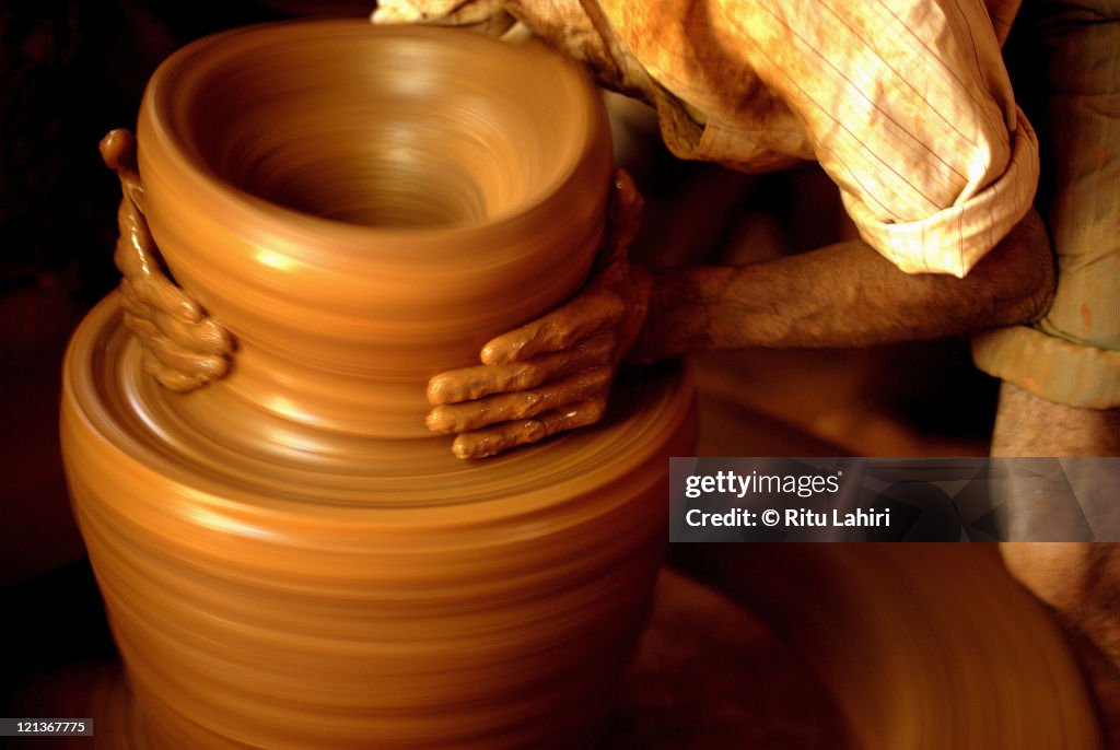 Potter making clay pot at wheel