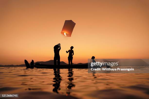 silhouette friends on the rooftop releasing chinese lantern - lanterna cinese foto e immagini stock