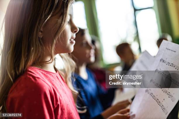 écolière pratiquant avec la partition sur une classe à l’école. - enfant chant classe photos et images de collection