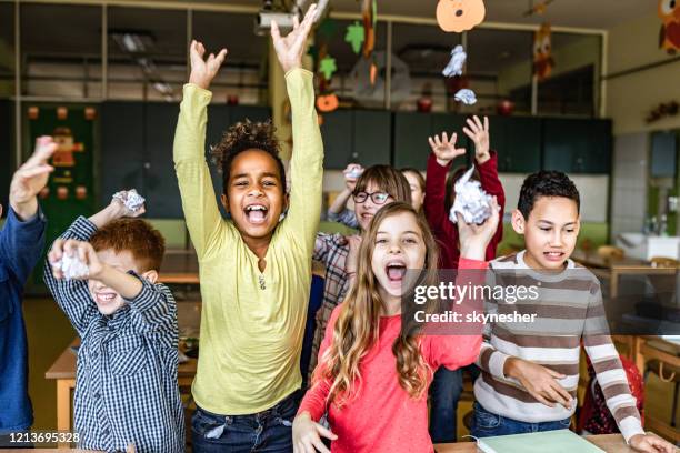 schulkinder sind frustriert, wenn sie papiere in einer klasse benutzen und sie in die kamera werfen. - mädchen frech stock-fotos und bilder