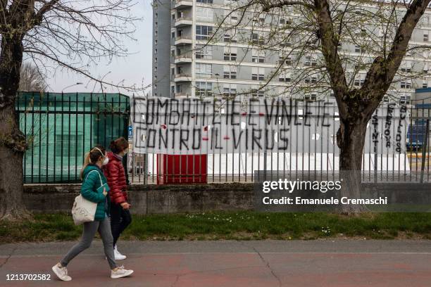 Two pedestrians walk past a banner that reads 'Fight and win against the virus' in front of Cremona Hospital on March 20, 2020 in Cremona, near...