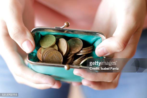 woman holding purse full of coins - women euro stock-fotos und bilder