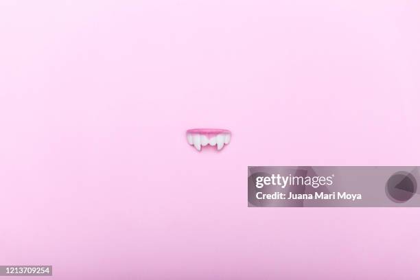 denture-shaped candy with vampire fangs, on a pink background. minimalist image - vampire teeth stock pictures, royalty-free photos & images