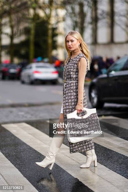 Lexi Fargo wears earrings, a Chanel bag with tweed, a tweed checked dress, a brown turtleneck, white boots, outside Rokh, during Paris Fashion Week -...