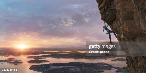 female free climber scaling steep coastal rock face at dawn - clambering imagens e fotografias de stock