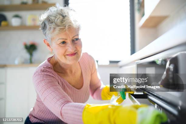 front view of senior woman indoors at home, cleaning kitchen. - clean kitchen stock pictures, royalty-free photos & images