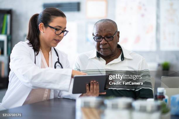 elderly man meets with a female doctor stock photo - pharmacist and patient stock pictures, royalty-free photos & images