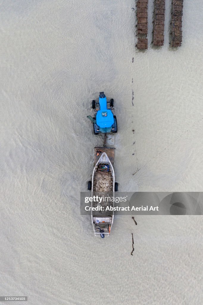 Close up aerial shot of a tractor towing a boat from the ocean, France