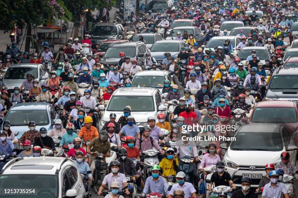 Motorbike riders with face masks are stuck in traffic during the morning peak hour on May 19, 2020 in Hanoi, Vietnam. Though some restrictions remain...