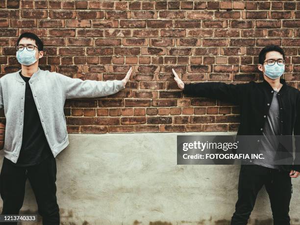 covid-19 sociale distantiëring, tieners handen tegen buitenmuur - asian twins stockfoto's en -beelden