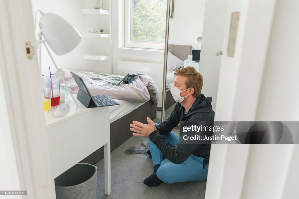 Man in mask meditating in bedroom