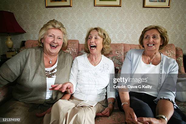 Three women sitting on couch sharing joke