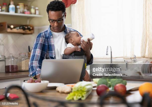 father working from home holding baby - multitasking parent stock pictures, royalty-free photos & images