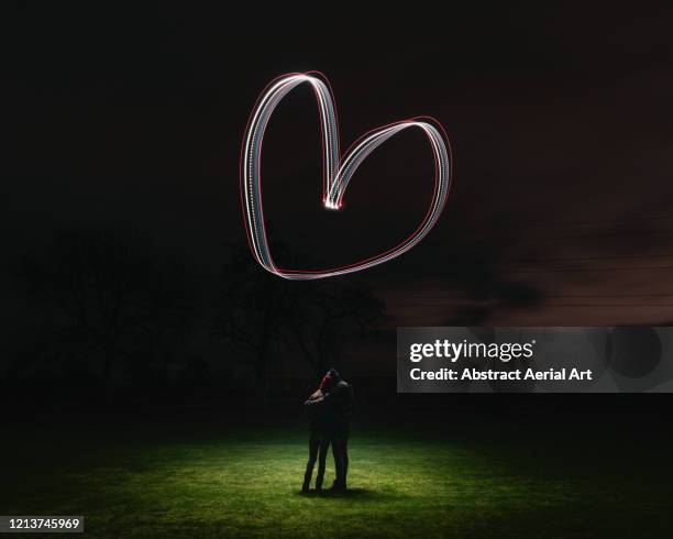 long exposure shot of a heart shape drawn by a drone above a couple in love, united kingdom - an evening with heart fotografías e imágenes de stock