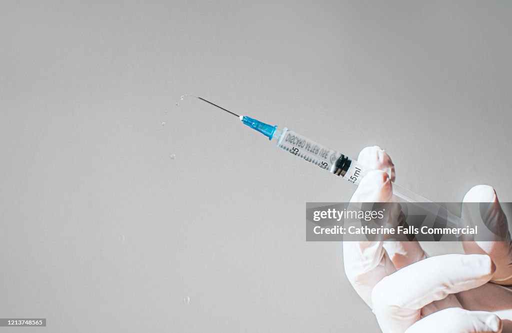 Gloved Hand holding a Syringe
