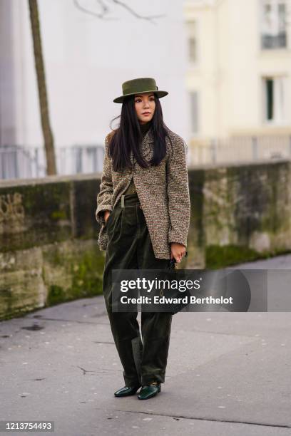 Yoyo Cao wears a green khaki hat from Ruslan Baginskiy, a Chanel tweed jacket, a green rigid case bag with crocodile pattern, green/khaki pants,...