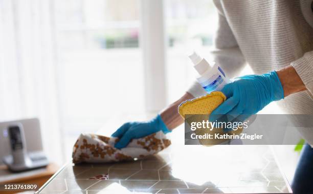 woman cleaning table with disinfectant spray, close-up of hands in protective gloves - reinigungsmittel stock-fotos und bilder