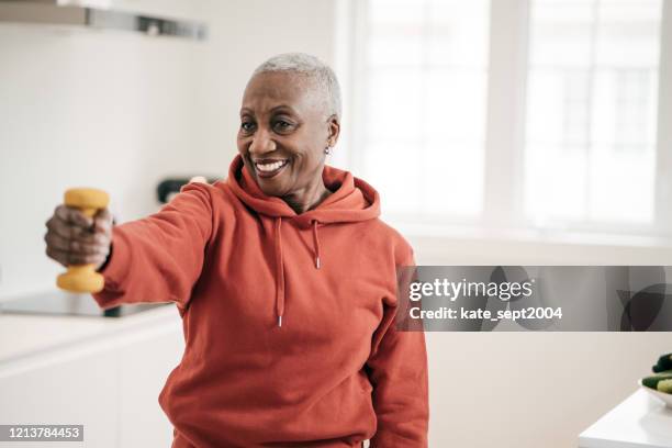 senior women taking care of herself  she exercise with  dumbbells at home - home stretching stock pictures, royalty-free photos & images