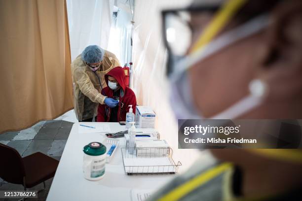 Doctor examines Juan Vasquez for a COVID-19 test inside a testing tent at St. Barnabas hospital on March 20, 2020 in New York City. St. Barnabas...