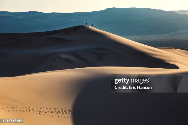 two hikers atop a giant sand dune in death valley - great basin fotografías e imágenes de stock