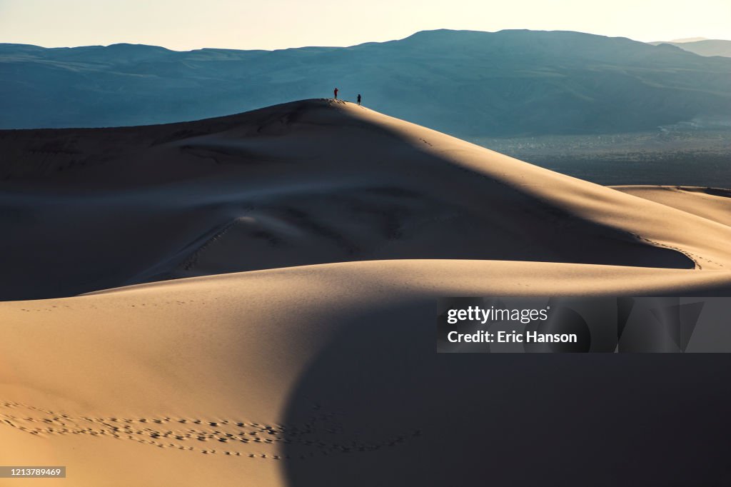 Two hikers atop a giant sand dune in Death Valley