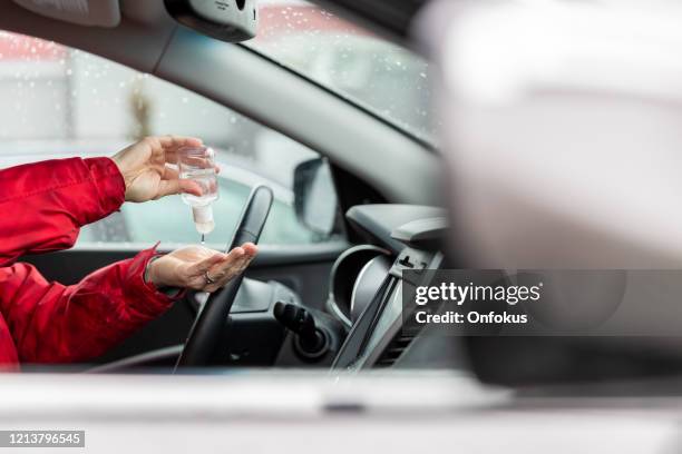 woman using hand sanitizer while sitting in car - hand sanitizer in car stock pictures, royalty-free photos & images