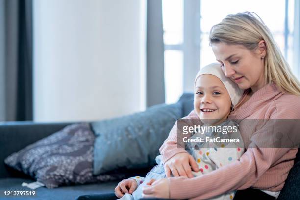 mother embracing her daughter with cancer stock photo - childhood cancer stock pictures, royalty-free photos & images