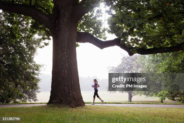woman jogging in suburban park - joggerin stock-fotos und bilder