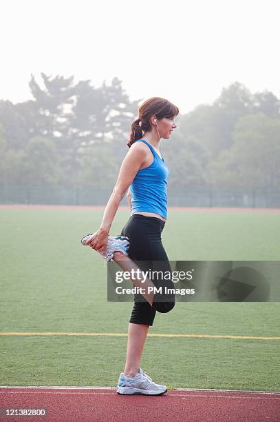 woman stretching on running track - quadriceps muscle stock pictures, royalty-free photos & images