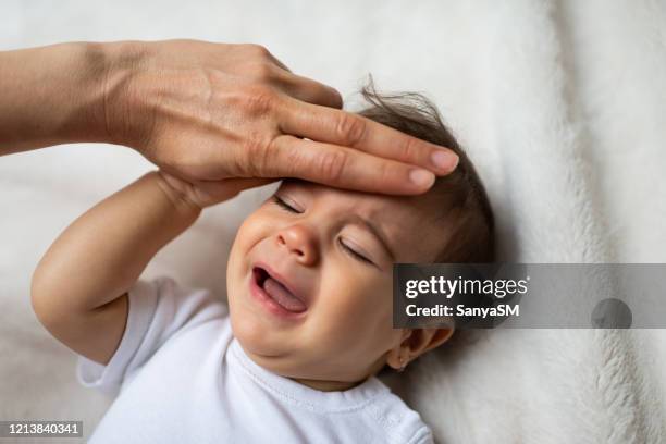 madre preocupada que mide la temperatura del bebé en el dormitorio - fever fotografías e imágenes de stock