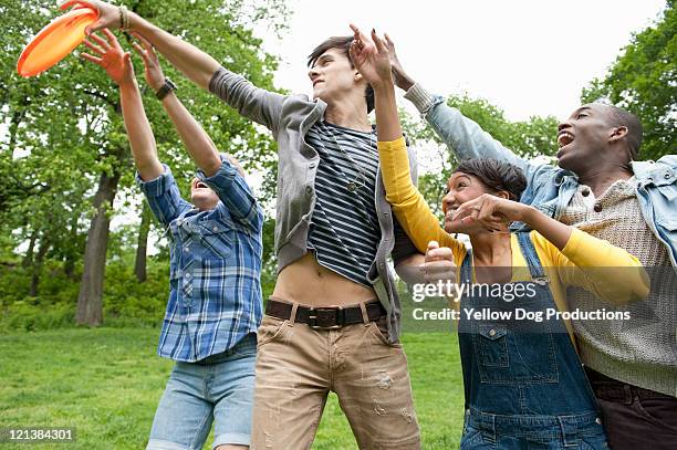 young adults playing frisbee  in the park - catch 22 foto e immagini stock