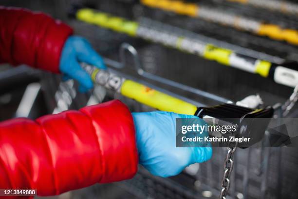 woman taking out shopping cart, wearing protective gloves - infectious disease stock pictures, royalty-free photos & images