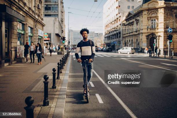 joven montando scooter eléctrico - riding scooter fotografías e imágenes de stock
