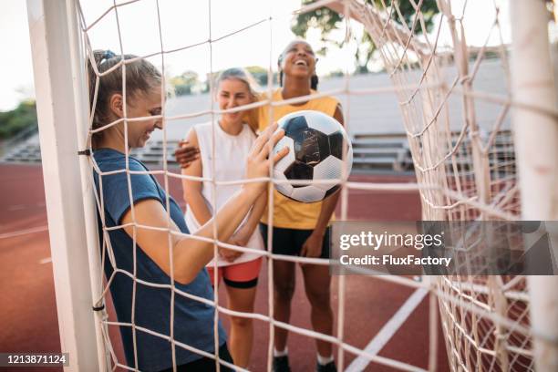 weibliche fußballsportler, die ein spiel auf einem sportplatz spielen - net sports equipment stock-fotos und bilder