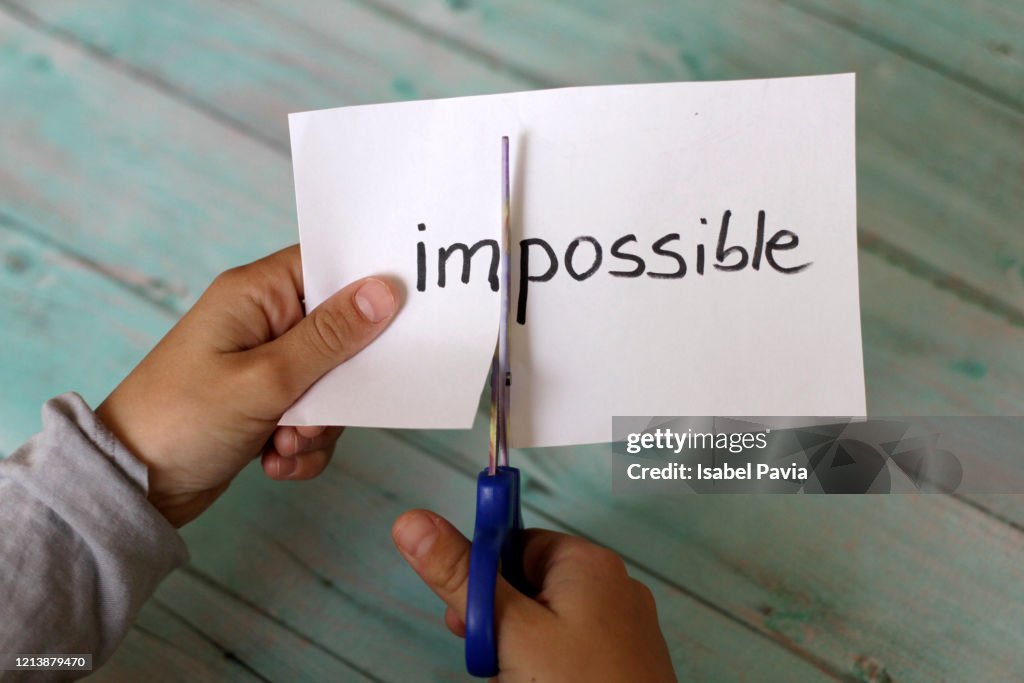 Hands Cutting Paper With Impossible Text