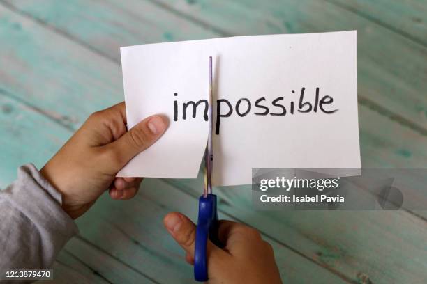 hands cutting paper with impossible text - mogelijk stockfoto's en -beelden
