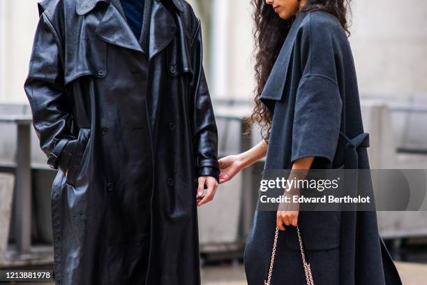 Guest wears a gray coat and holds the hand of another guest who wears a black leather coat, outside Rokh, during Paris Fashion Week - Womenswear...