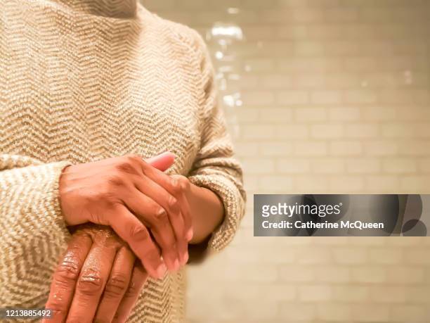 african-american woman rubs lotion on dry hands - irritation skin woman stock pictures, royalty-free photos & images