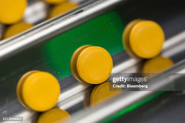 Finished tablets cascade down the channels of a packaging machine during the manufacture of the Favipiravir antiviral medicine, a joint venture...