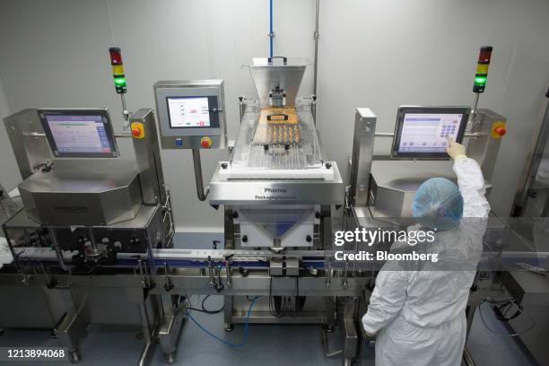 Worker wearing personal protective equipment operates a packaging machine during the manufacture of the Favipiravir antiviral medicine, a joint...