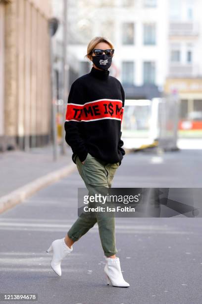 Influencer Gitta Banko, wearing a black turtleneck pullover with a red stripe with black lettering by Jacob lee, green pants in utility style by...