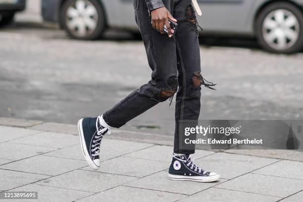 A guest wears black ripped jeans, Converse sneakers, outside... News Photo - Getty Images A guest wears black ripped jeans, Converse sneakers, outside... News Photo - Getty Images