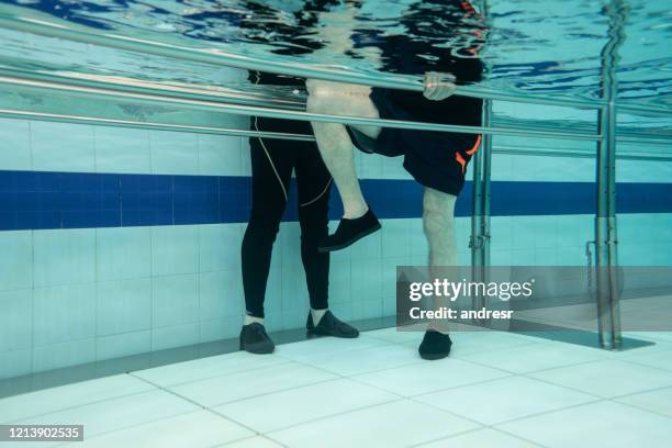 hogere mens die fysiotherapieoefeningen in het water doet - aquatic therapy stockfoto's en -beelden