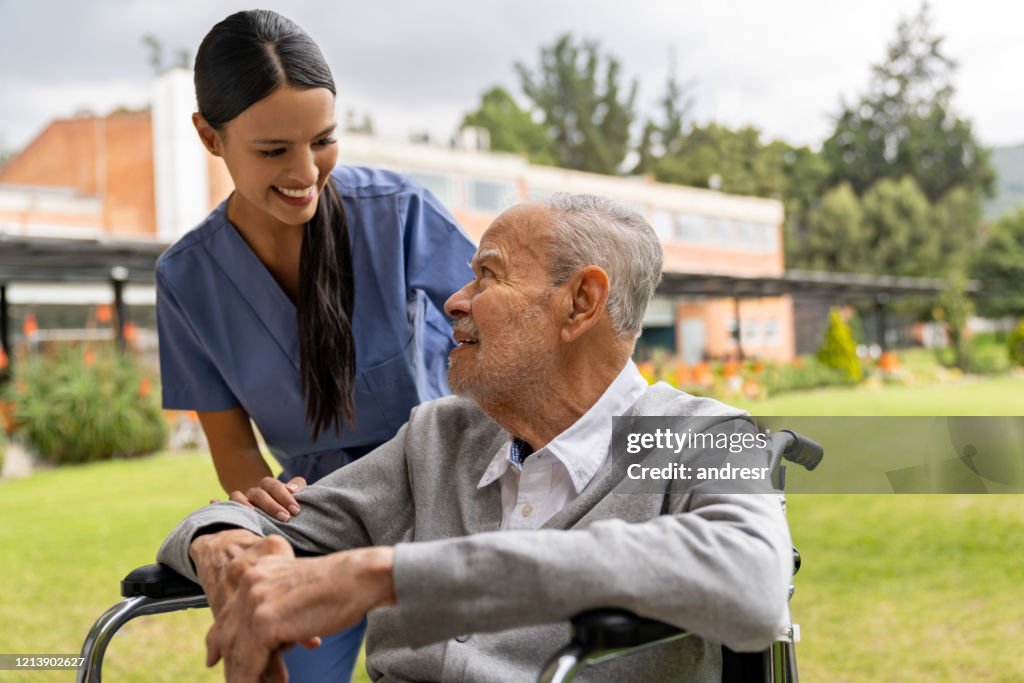 Nurse greeting senior patient in the gardens of the hospital