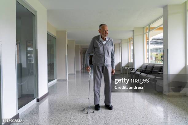 adulto anziano in ospedale a piedi con un bastone - bastone da passeggio foto e immagini stock