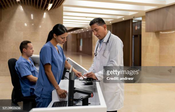 doctor talking to a nurse in the reception at the hospital - secretary stock pictures, royalty-free photos & images