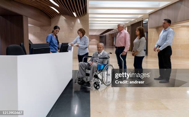 patients in line waiting to register at the hospital - hospital reception stock pictures, royalty-free photos & images
